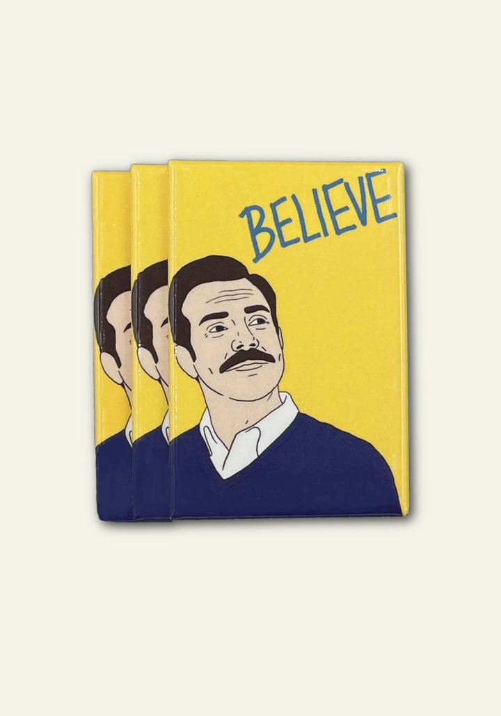 Three yellow magnets with a graphic of Ted Lasso and the word &