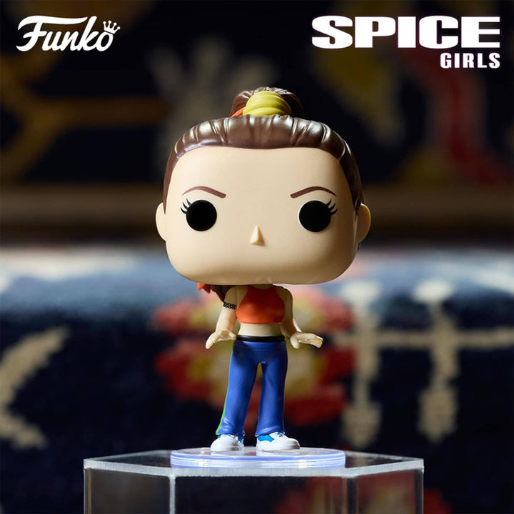 Funko Spice Girls collectible vinyl figure of Mel Gibson as Girl with the Dragon Tattoo, standing on a clear acrylic display base. The figure features brown hair in a bun, a red crop top, blue pants, and white sneakers.
